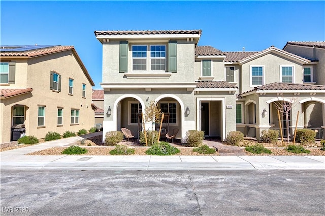 mediterranean / spanish-style house featuring a residential view, covered porch, a tiled roof, and stucco siding