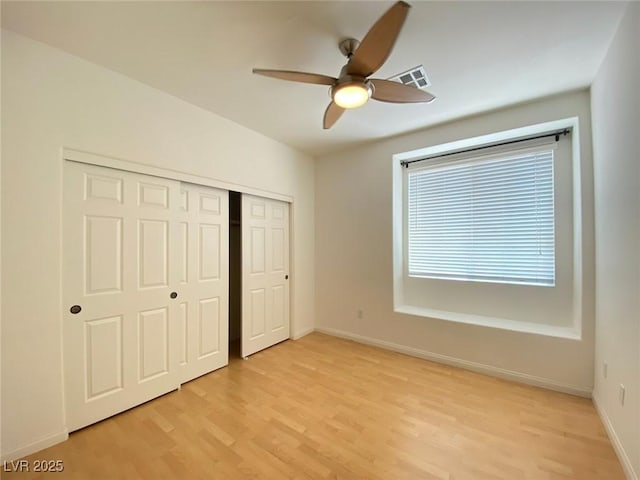 unfurnished bedroom with baseboards, visible vents, ceiling fan, light wood-type flooring, and a closet