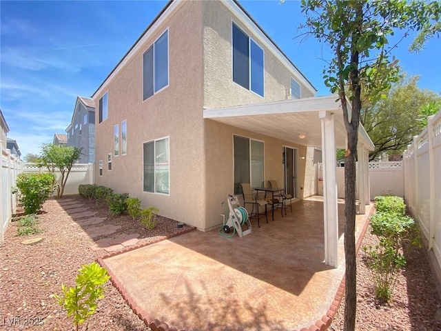 rear view of property featuring a fenced backyard, a patio, and stucco siding