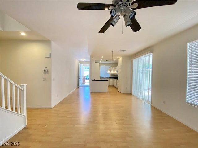 unfurnished living room featuring light wood-style floors, recessed lighting, baseboards, and stairs