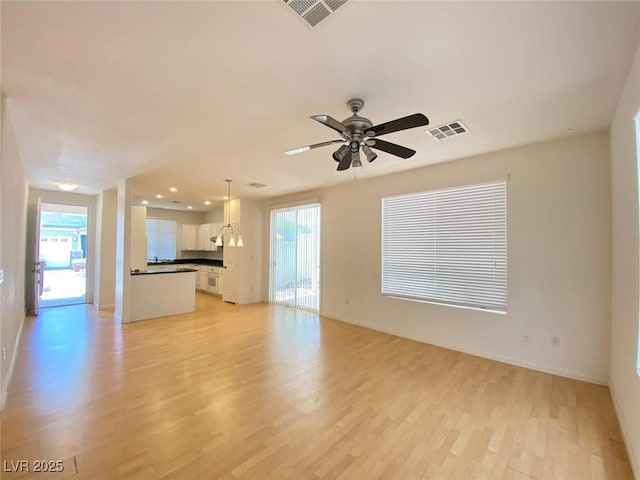 unfurnished living room with light wood-style floors, visible vents, and a wealth of natural light