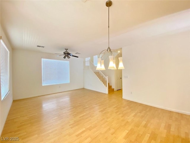 unfurnished room with baseboards, visible vents, light wood finished floors, and ceiling fan with notable chandelier