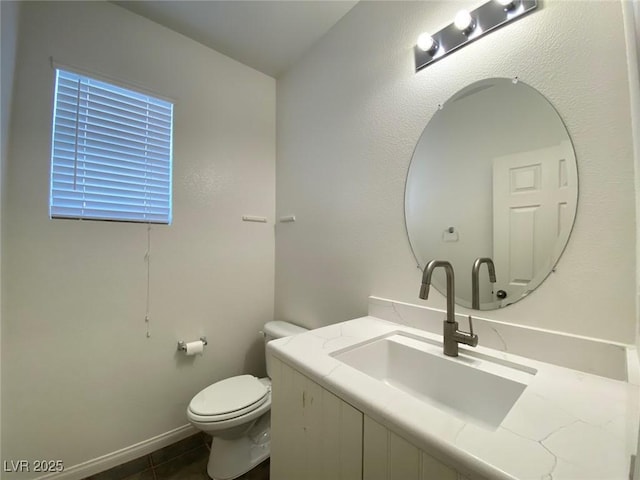 bathroom with toilet, tile patterned floors, baseboards, and vanity