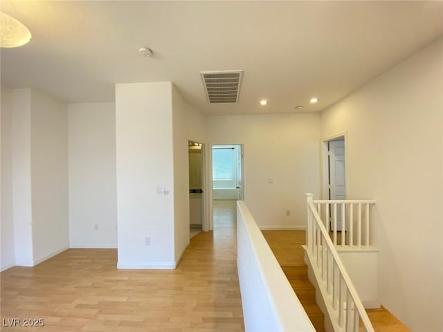 hallway with recessed lighting, visible vents, baseboards, an upstairs landing, and light wood-type flooring