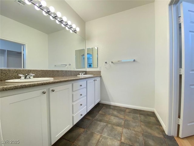 full bathroom with a sink, baseboards, and double vanity