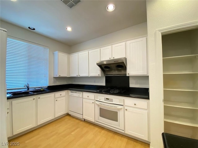 kitchen with under cabinet range hood, white appliances, a sink, visible vents, and light wood finished floors