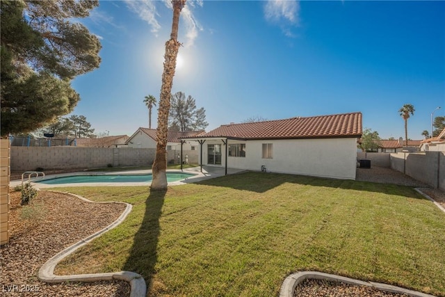 back of property featuring a fenced backyard, a tiled roof, a lawn, a fenced in pool, and stucco siding