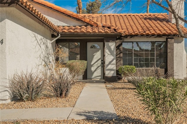 property entrance with a tile roof and stucco siding