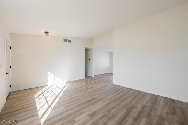 empty room featuring light wood-style floors, visible vents, and baseboards