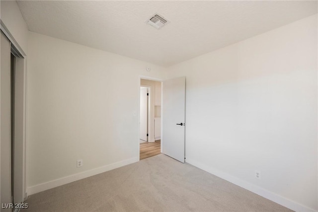 unfurnished bedroom with light carpet, a closet, visible vents, and baseboards