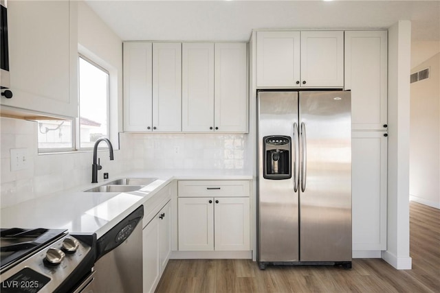 kitchen featuring appliances with stainless steel finishes, a sink, visible vents, and white cabinetry