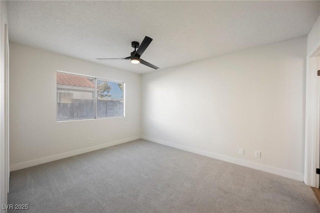 carpeted empty room with a ceiling fan, baseboards, and a textured ceiling