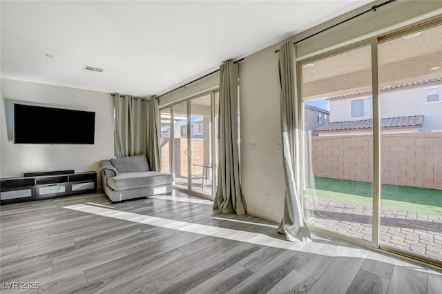 unfurnished living room with a wall of windows, visible vents, and wood finished floors