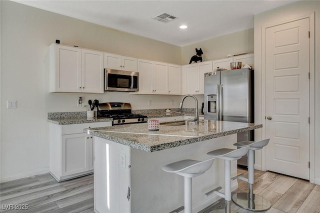 kitchen featuring light wood finished floors, visible vents, stainless steel appliances, and a sink