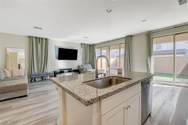 kitchen featuring visible vents, dishwasher, light wood-style flooring, open floor plan, and a sink