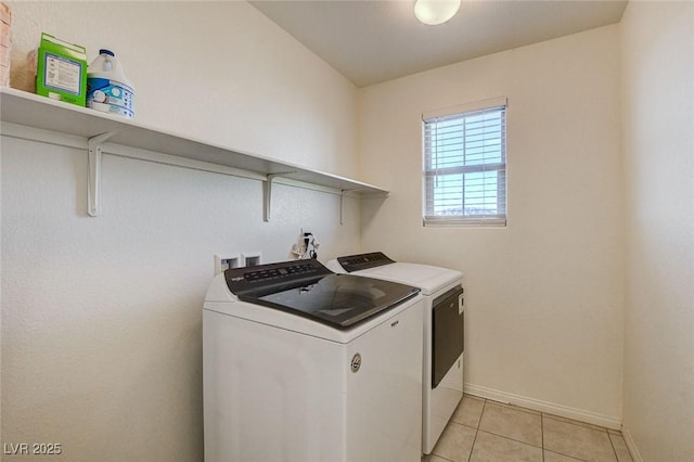 washroom with laundry area, washer and clothes dryer, baseboards, and light tile patterned floors