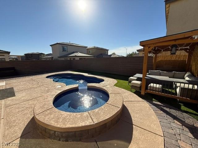 view of swimming pool with a patio, a pool with connected hot tub, a fenced backyard, and an outdoor living space