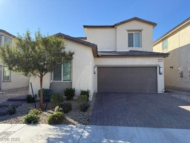 traditional home with a garage, decorative driveway, and stucco siding