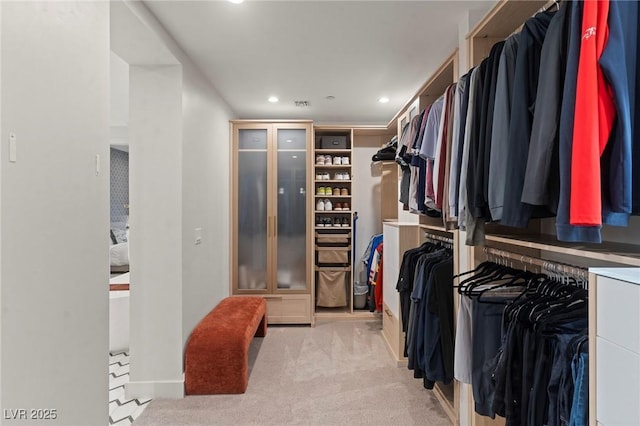 walk in closet with visible vents and light colored carpet