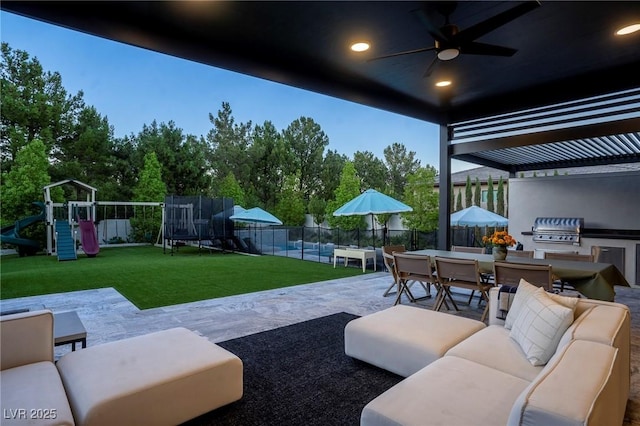 view of patio featuring playground community, outdoor lounge area, fence, exterior kitchen, and outdoor dining space