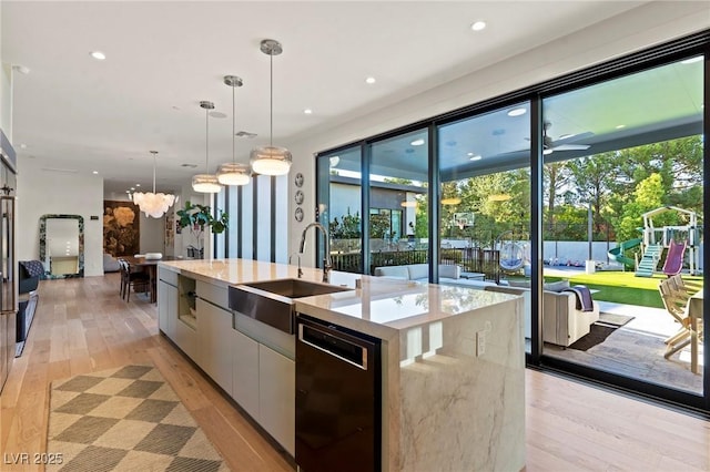 kitchen featuring black dishwasher, a spacious island, light wood-style floors, a sink, and modern cabinets