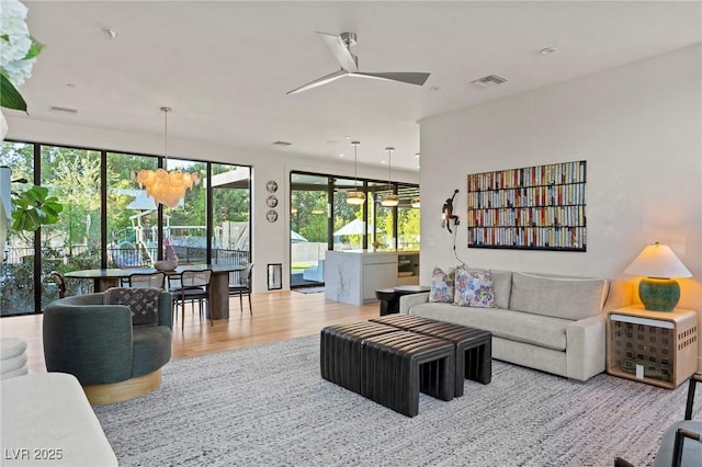 living room featuring a ceiling fan, visible vents, and wood finished floors