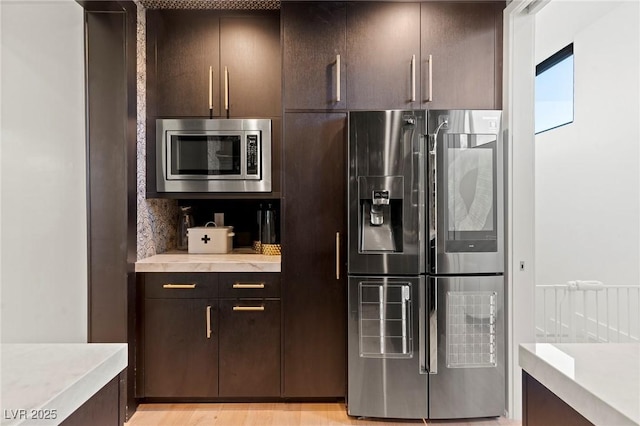 kitchen featuring dark brown cabinetry, appliances with stainless steel finishes, and light countertops