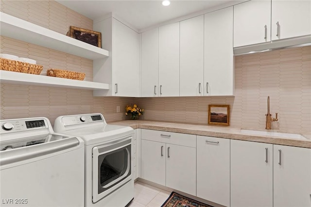 clothes washing area with light tile patterned floors, a sink, cabinet space, and washer and dryer