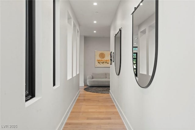 hall with recessed lighting, light wood-style flooring, baseboards, and a barn door