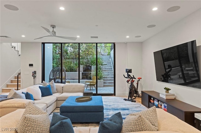 living area featuring a wall of windows, recessed lighting, visible vents, and stairs