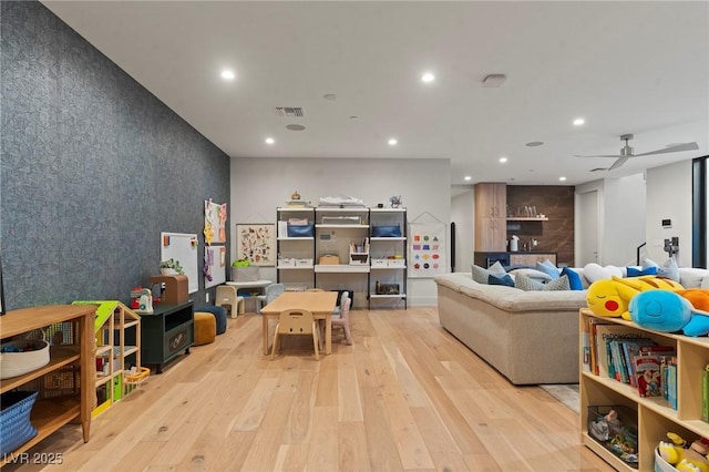 recreation room featuring visible vents, wood-type flooring, an accent wall, ceiling fan, and recessed lighting