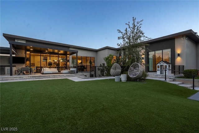 back of house with an outbuilding, a patio area, a lawn, and an outdoor hangout area