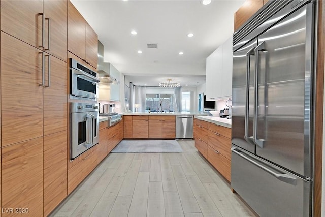 kitchen featuring a peninsula, modern cabinets, appliances with stainless steel finishes, and light countertops