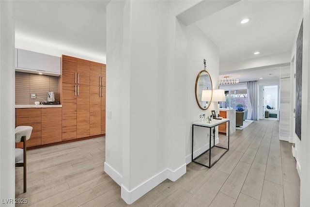 corridor with light wood-type flooring, baseboards, and recessed lighting