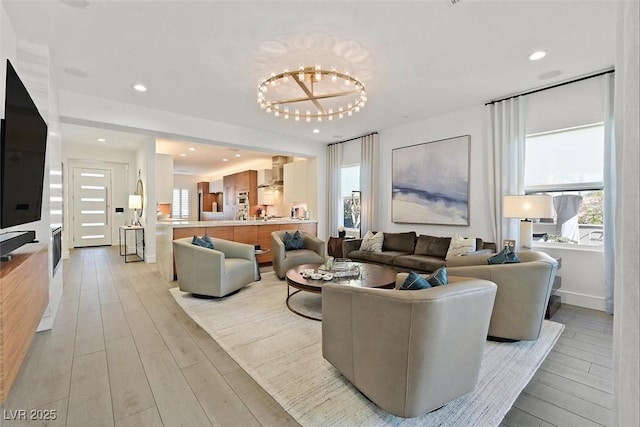 living area with light wood-style floors, recessed lighting, and an inviting chandelier