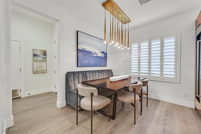 dining area featuring wood finished floors, visible vents, and baseboards