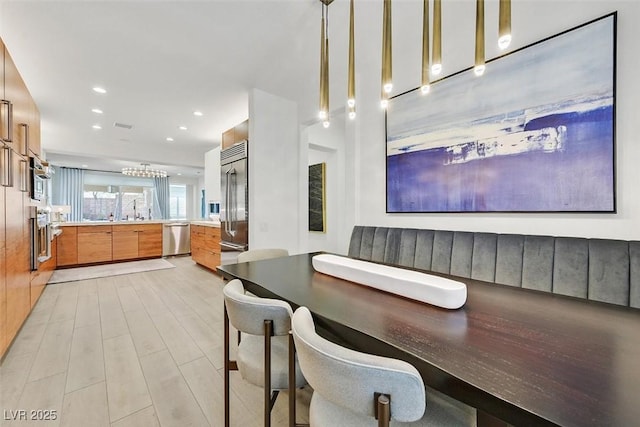 kitchen featuring brown cabinets, stainless steel appliances, recessed lighting, light wood-style flooring, and modern cabinets