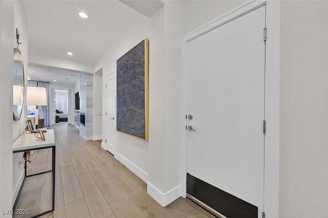 corridor featuring light wood-type flooring, baseboards, and recessed lighting