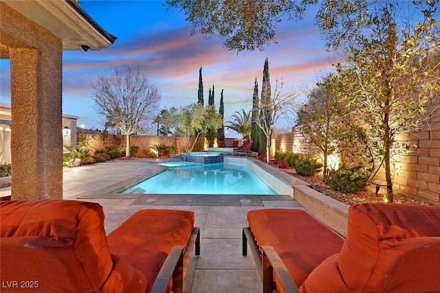 pool at dusk featuring a fenced backyard, a pool with connected hot tub, and a patio