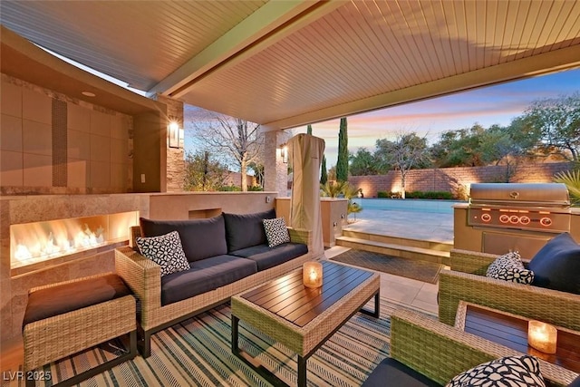 patio terrace at dusk with a grill, fence, and an outdoor living space