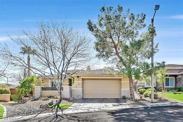 view of front of home with a garage, decorative driveway, a fenced front yard, and stucco siding