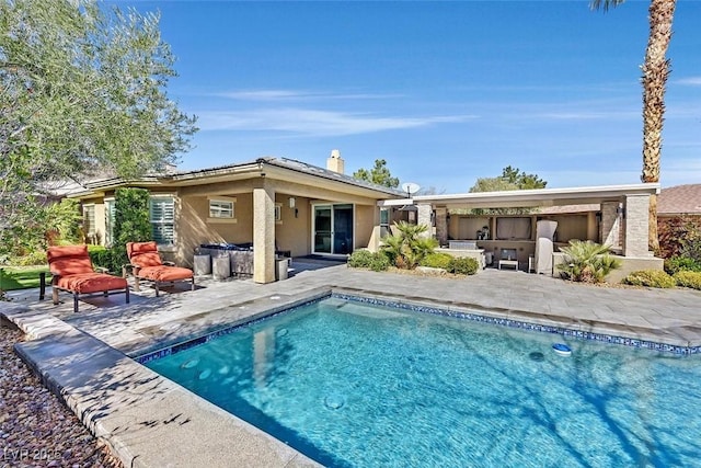 back of property with stucco siding, a chimney, an outdoor pool, and a patio