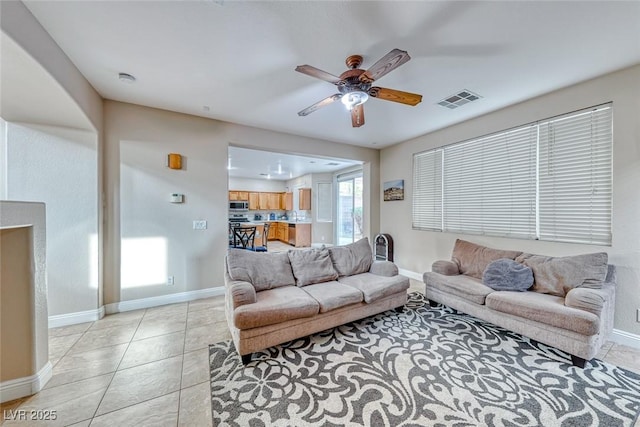 living room featuring a ceiling fan, visible vents, baseboards, and light tile patterned flooring