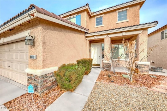 doorway to property featuring an attached garage and stucco siding