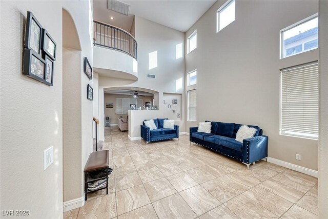 10332 George Hart Ct, Las Vegas, NV 89129 - living room with arched walkways, a high ceiling, baseboards, ceiling fan, and marble finish flooring