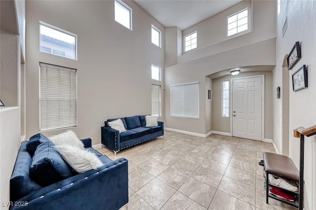 living area featuring a high ceiling and baseboards