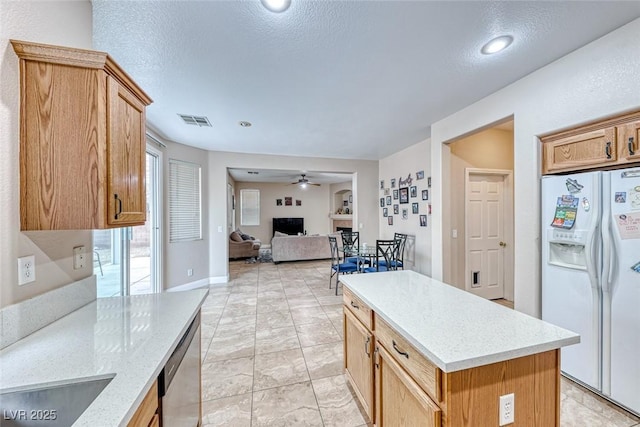 kitchen featuring ceiling fan, white refrigerator with ice dispenser, a fireplace, visible vents, and stainless steel dishwasher