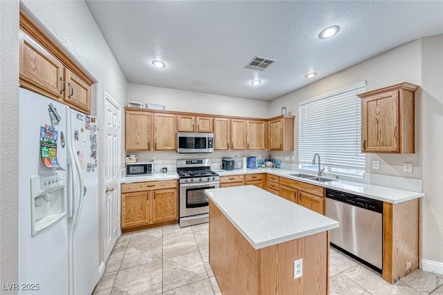 kitchen with a sink, visible vents, light countertops, appliances with stainless steel finishes, and a center island