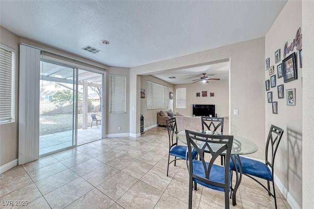 dining area with baseboards, ceiling fan, visible vents, and a textured ceiling