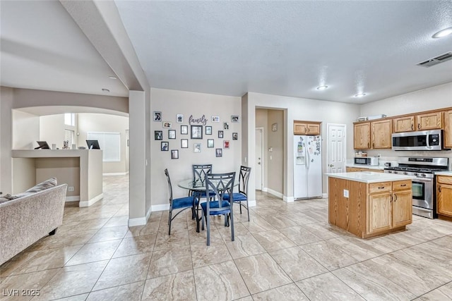 kitchen with visible vents, open floor plan, a center island, stainless steel appliances, and light countertops